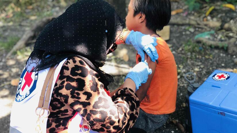 A volunteer from the Philippine Red Cross delivers a vaccination against measles to a young boy in Cotabato, Philippines in April 2024.