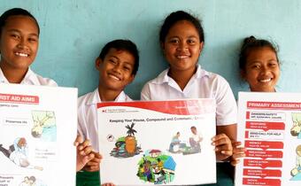 Schoolchildren in Funafuti, Tuvalu take part in a first aid training session at their school and hold up posters showing what they have learned