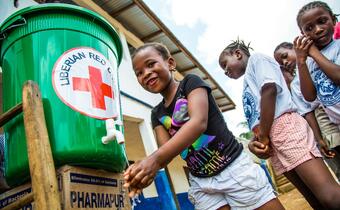 School children practice proper handwashing at a water point installed by the Liberian Red Cross before classes start in Montserrado, Liberia in October 2015.