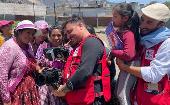 IFRC comms officials show video footage they've captured to women living in rural western Guatemala, who smile at seeing themselves on camera.