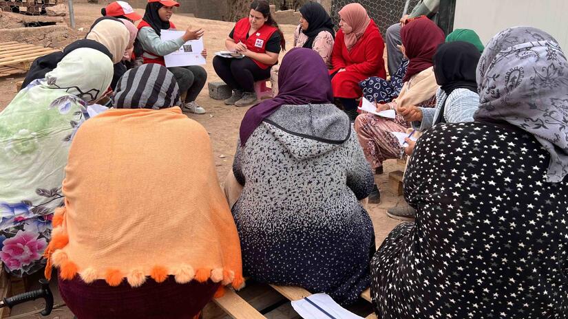 Un volontaire du Croissant-Rouge marocain explique à une douzaine de femmes du village d'Ait Youssef comment fabriquer leurs propres produits d'hygiène menstruelle.
