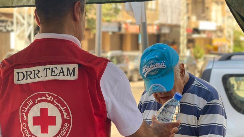 A member of the Lebanese Red Cross Disaster Risk Reduction team shares a water bottle with an elderly man as part of a comprehensive plan to get ahead of heatwave season.